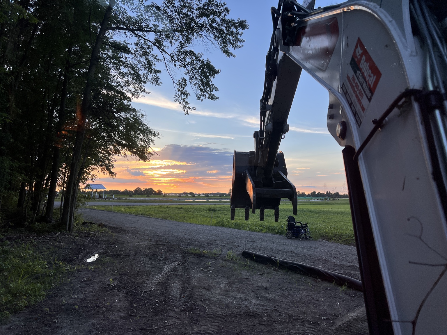 Excavator beside a newly graded gravel drive at sunset